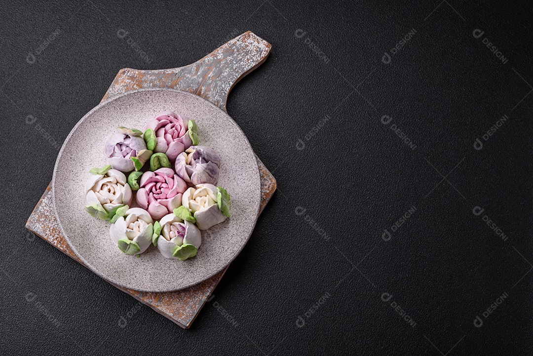 Lindos e saborosos marshmallows em forma de botões de tulipa sobre um fundo escuro de concreto