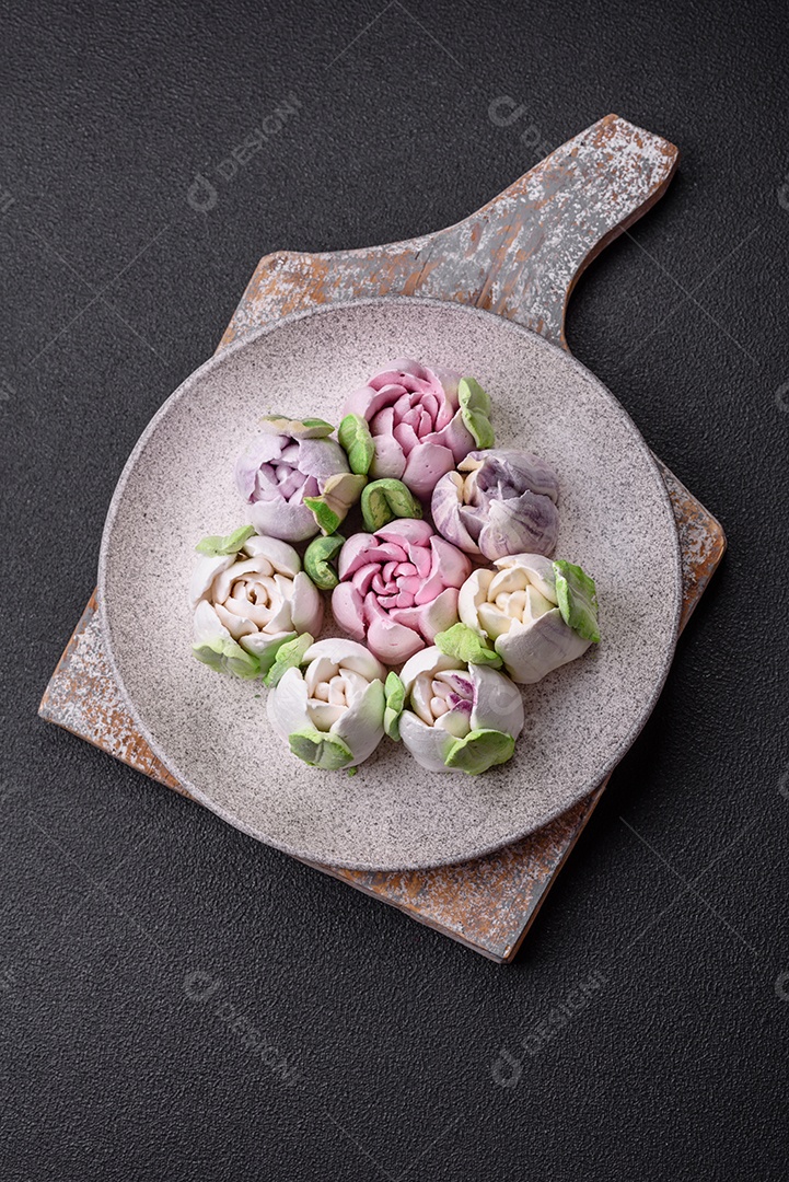 Lindos e saborosos marshmallows em forma de botões de tulipa sobre um fundo escuro de concreto