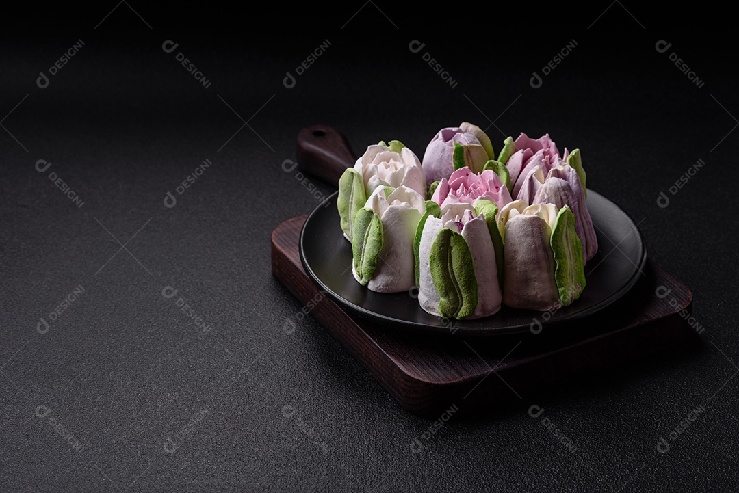 Lindos e saborosos marshmallows em forma de botões de tulipa sobre um fundo escuro de concreto