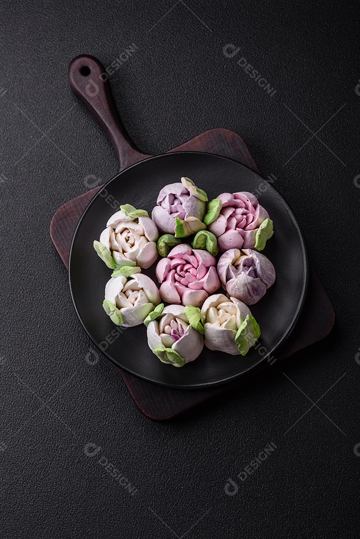 Lindos e saborosos marshmallows em forma de botões de tulipa sobre um fundo escuro de concreto