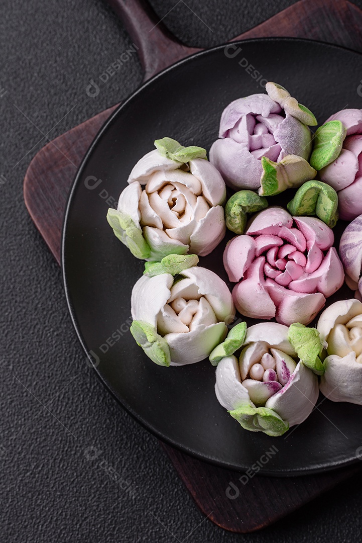 Lindos e saborosos marshmallows em forma de botões de tulipa sobre um fundo escuro de concreto
