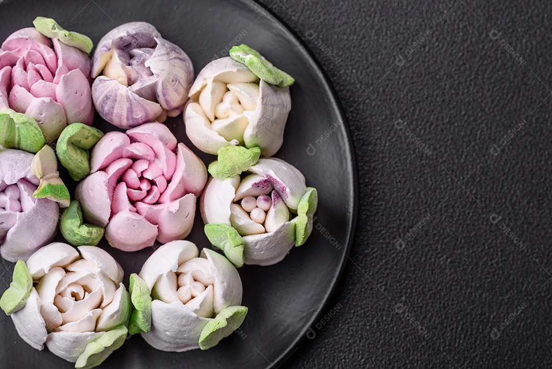 Lindos e saborosos marshmallows em forma de botões de tulipa sobre um fundo escuro de concreto