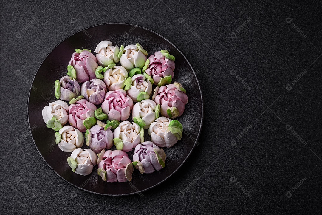 Lindos e saborosos marshmallows em forma de botões de tulipa sobre um fundo escuro de concreto