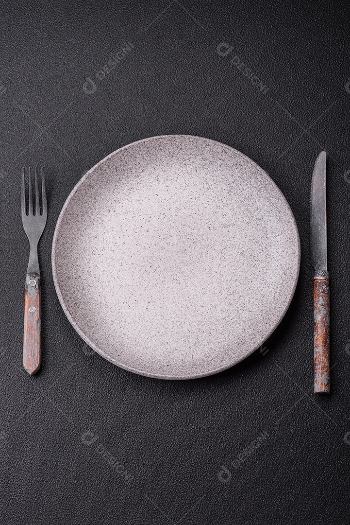 Garfo de talheres, faca e colher sobre um fundo de concreto texturizado escuro. Itens e acessórios de cozinha