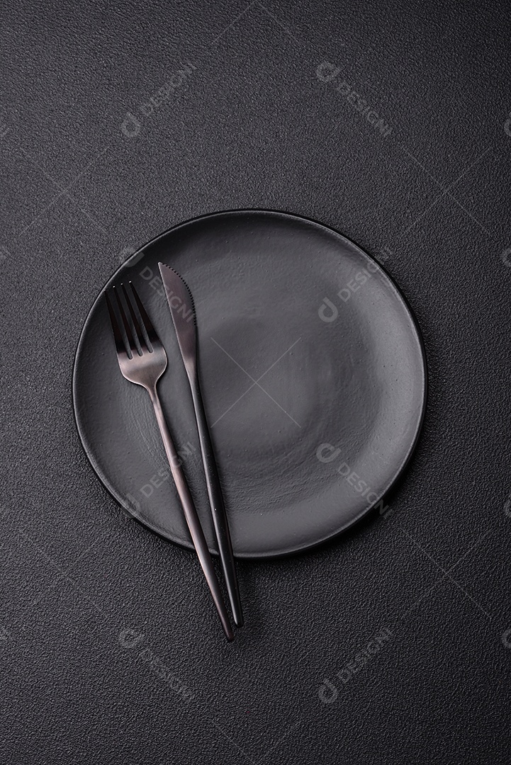 Garfo de talheres, faca e colher sobre um fundo de concreto texturizado escuro. Itens e acessórios de cozinha