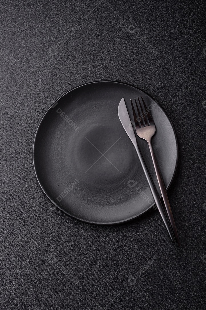 Garfo de talheres, faca e colher sobre um fundo de concreto texturizado escuro. Itens e acessórios de cozinha