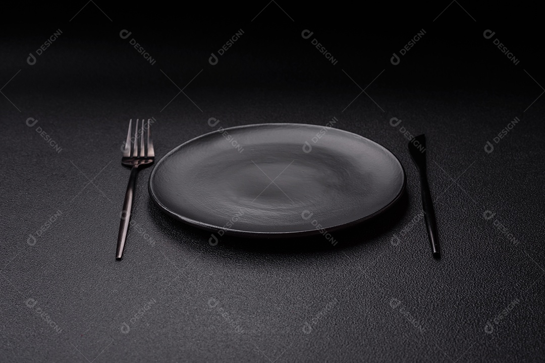 Garfo de talheres, faca e colher sobre um fundo de concreto texturizado escuro. Itens e acessórios de cozinha