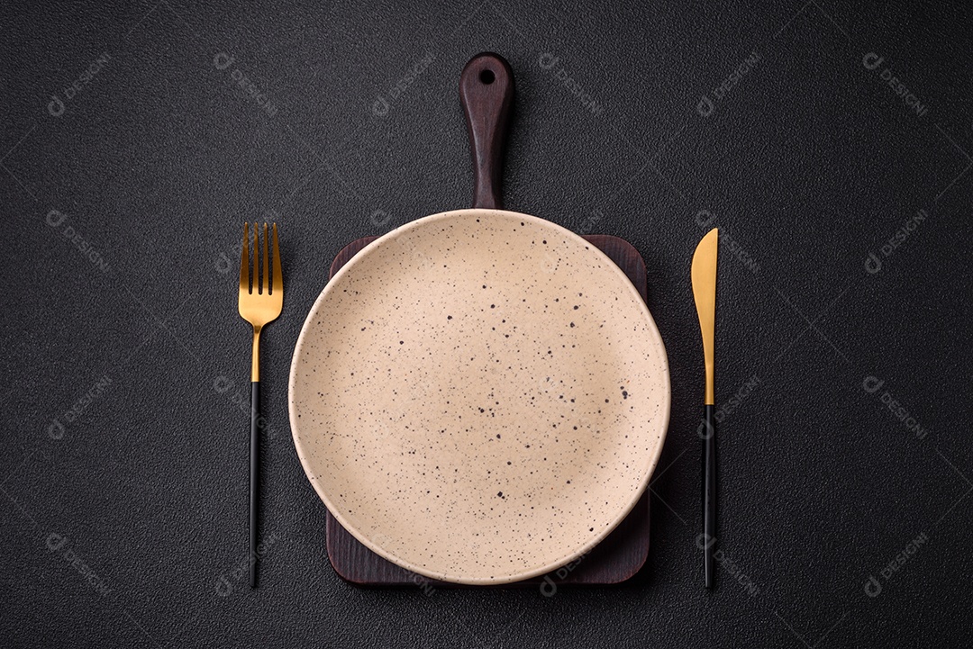 Garfo de talheres, faca e colher sobre um fundo de concreto texturizado escuro. Itens e acessórios de cozinha