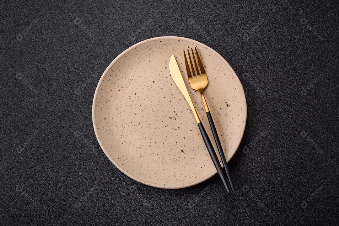 Garfo de talheres, faca e colher sobre um fundo de concreto texturizado escuro. Itens e acessórios de cozinha