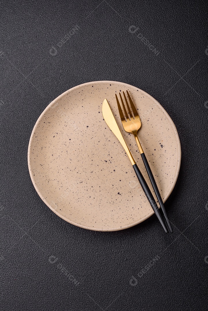 Garfo de talheres, faca e colher sobre um fundo de concreto texturizado escuro. Itens e acessórios de cozinha