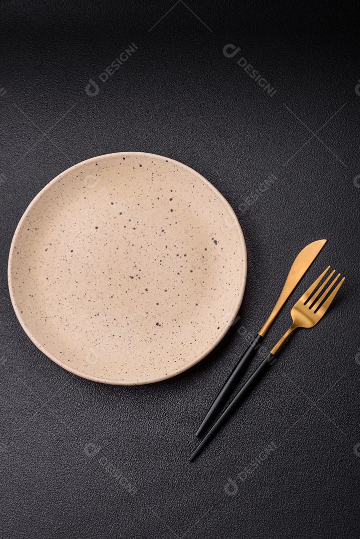 Garfo de talheres, faca e colher sobre um fundo de concreto texturizado escuro. Itens e acessórios de cozinha