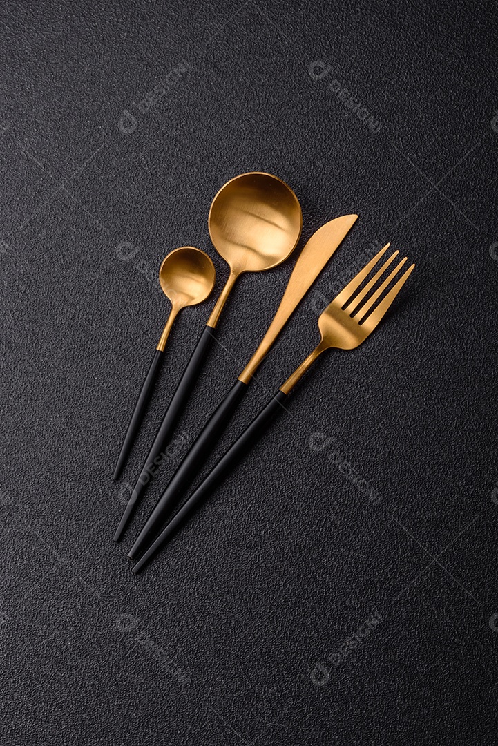 Garfo de talheres, faca e colher sobre um fundo de concreto texturizado escuro. Itens e acessórios de cozinha