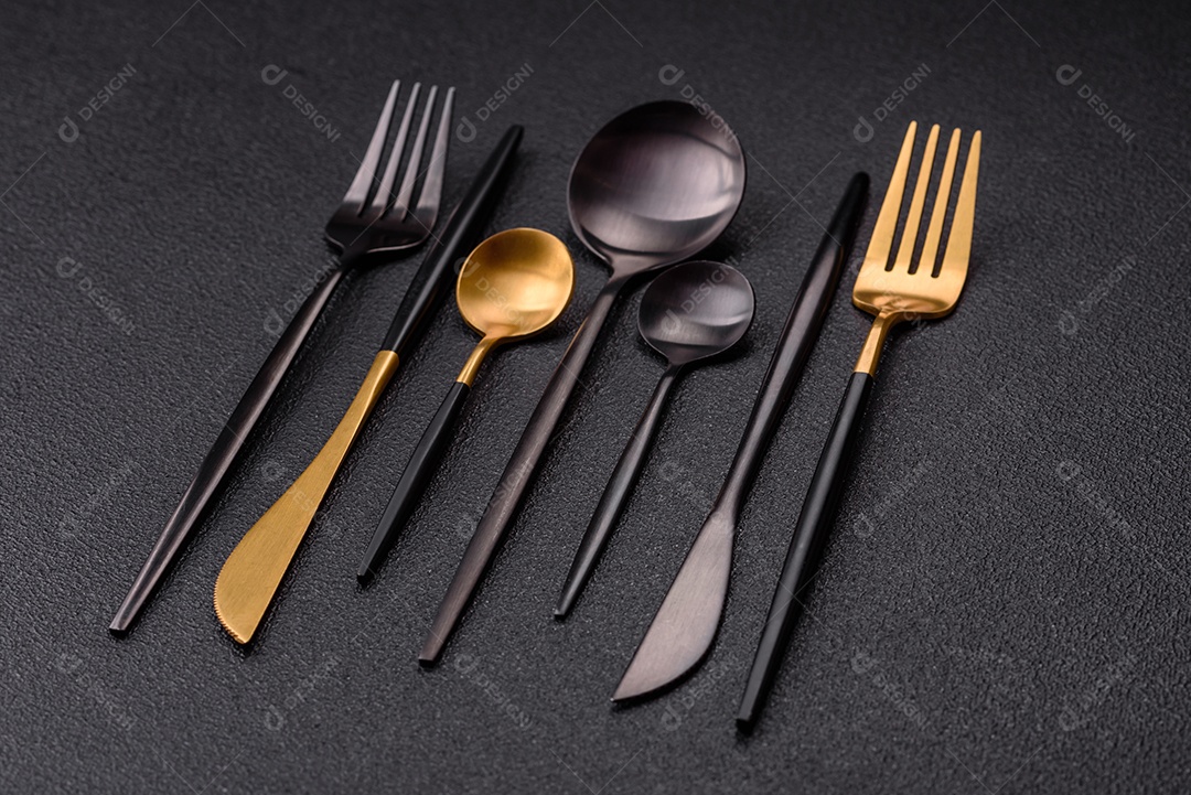 Garfo de talheres, faca e colher sobre um fundo de concreto texturizado escuro. Itens e acessórios de cozinha