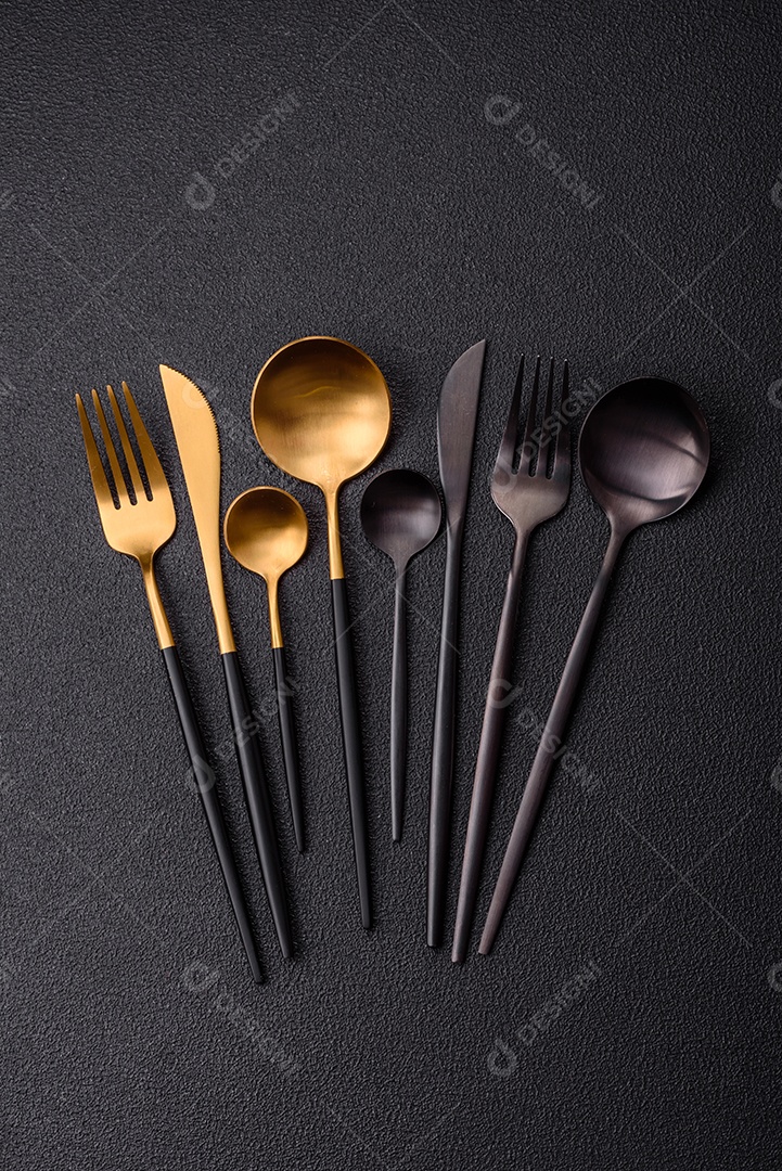 Garfo de talheres, faca e colher sobre um fundo de concreto texturizado escuro. Itens e acessórios de cozinha