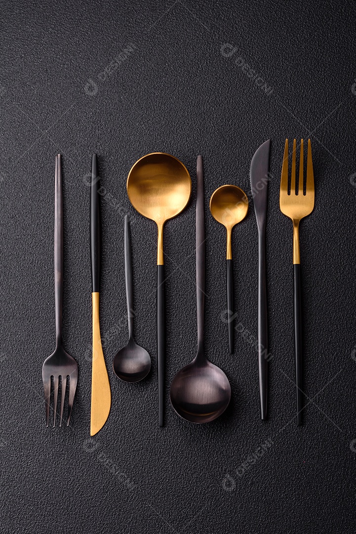 Garfo de talheres, faca e colher sobre um fundo de concreto texturizado escuro. Itens e acessórios de cozinha