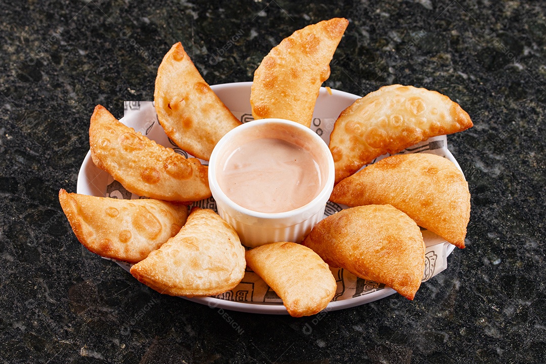 Porção de pasteis com molho no centro