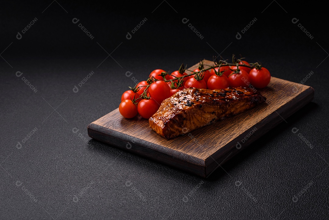 Delicioso salmão vermelho grelhado com molho e gergelim, especiarias e ervas sobre um fundo escuro de concreto