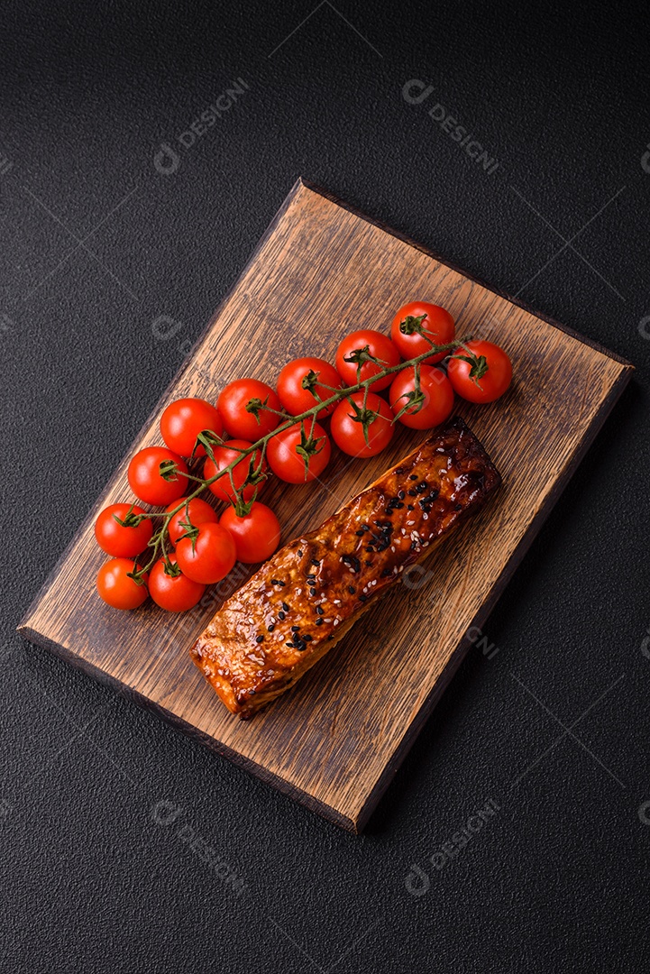 Delicioso salmão vermelho grelhado com molho e gergelim, especiarias e ervas sobre um fundo escuro de concreto