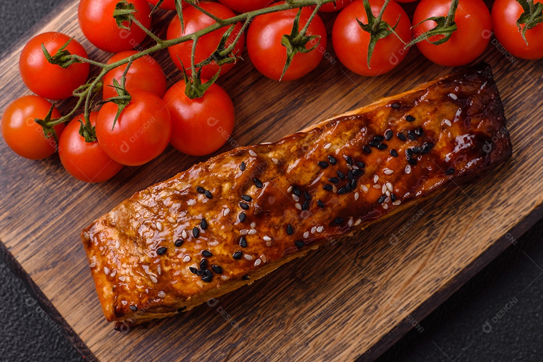 Delicioso salmão vermelho grelhado com molho e gergelim, especiarias e ervas sobre um fundo escuro de concreto