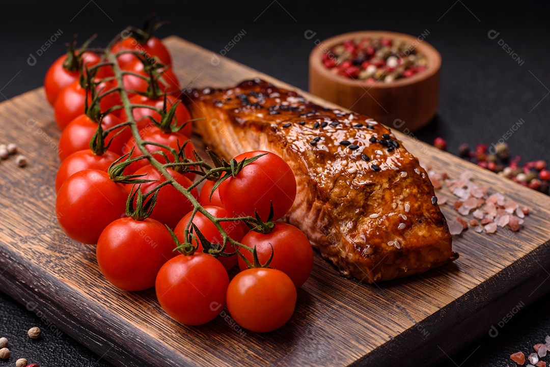 Delicioso salmão vermelho grelhado com molho e gergelim, especiarias e ervas sobre um fundo escuro de concreto