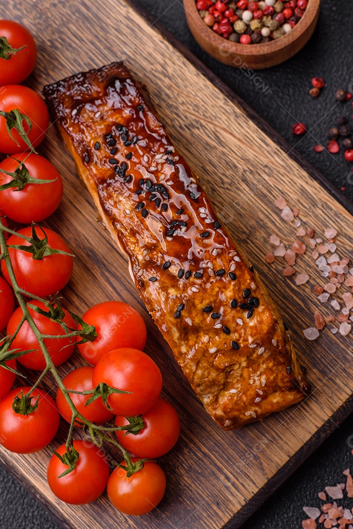 Delicioso salmão vermelho grelhado com molho e gergelim, especiarias e ervas sobre um fundo escuro de concreto