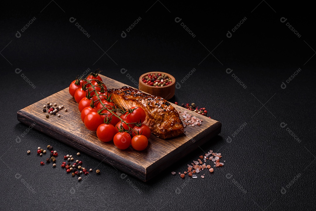 Delicioso salmão vermelho grelhado com molho e gergelim, especiarias e ervas sobre um fundo escuro de concreto
