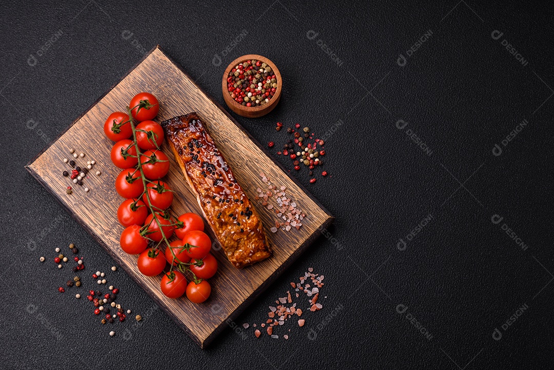 Delicioso salmão vermelho grelhado com molho e gergelim, especiarias e ervas sobre um fundo escuro de concreto