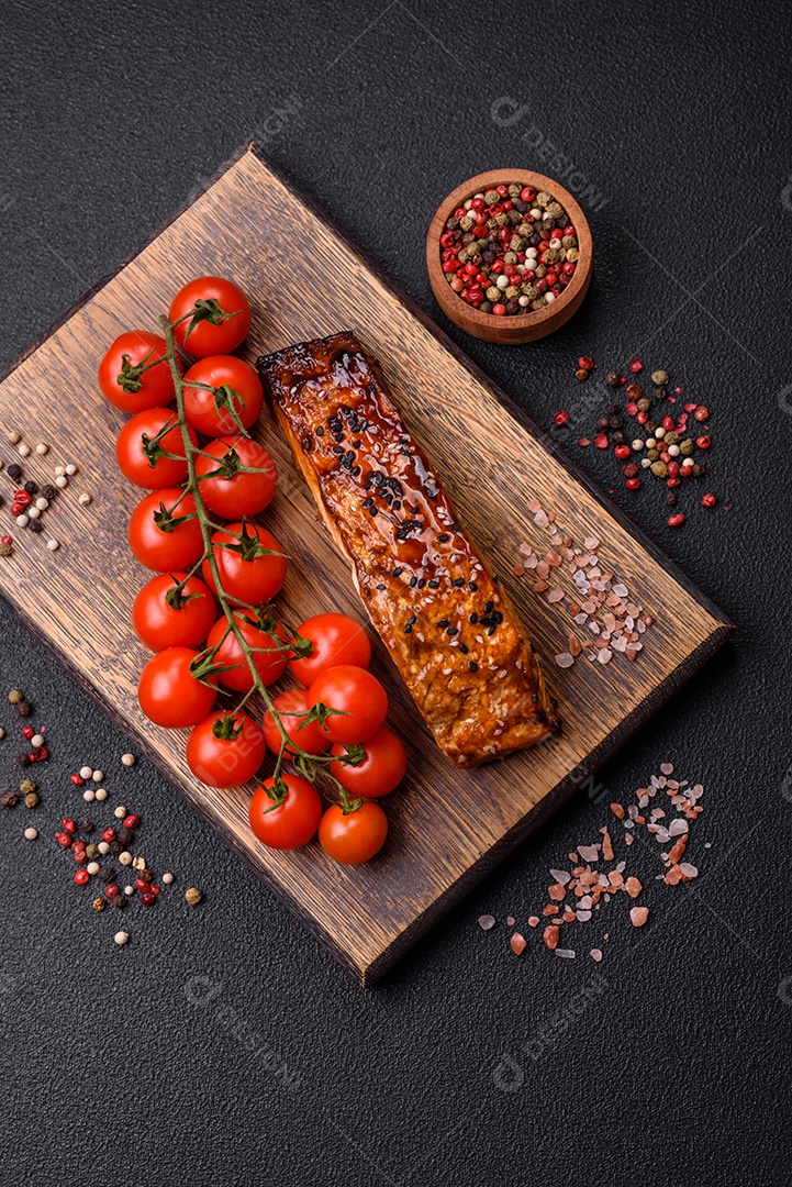 Delicioso salmão vermelho grelhado com molho e gergelim, especiarias e ervas sobre um fundo escuro de concreto