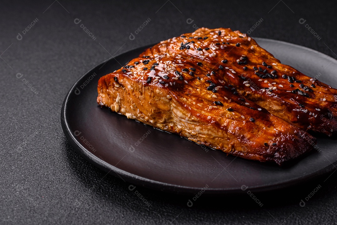 Delicioso salmão vermelho grelhado com molho e gergelim, especiarias e ervas sobre um fundo escuro de concreto