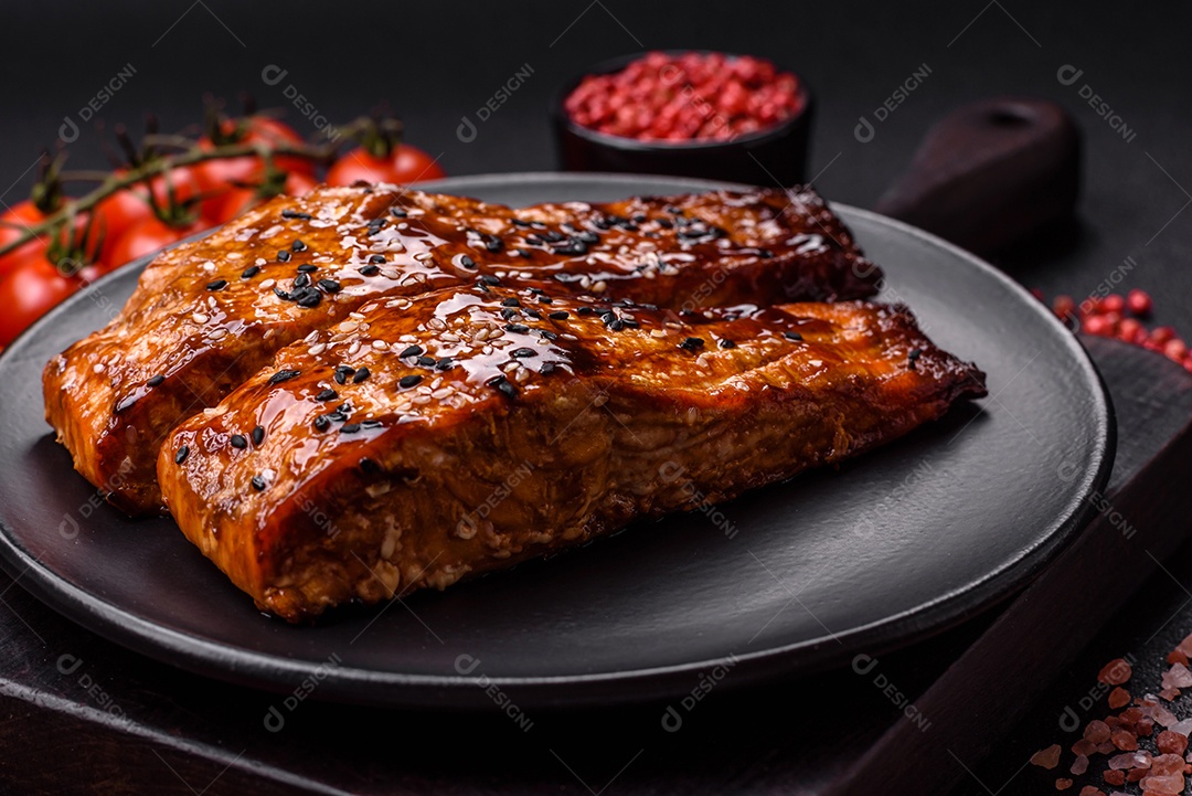 Delicioso salmão vermelho grelhado com molho e gergelim, especiarias e ervas sobre um fundo escuro de concreto