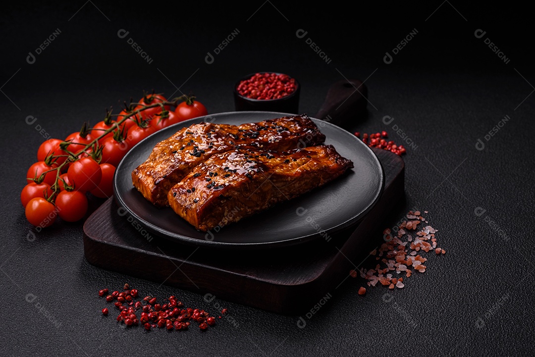 Delicioso salmão vermelho grelhado com molho e gergelim, especiarias e ervas sobre um fundo escuro de concreto