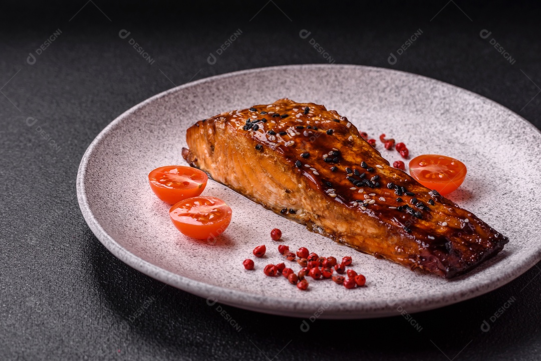 Delicioso salmão vermelho grelhado com molho e gergelim, especiarias e ervas sobre um fundo escuro de concreto