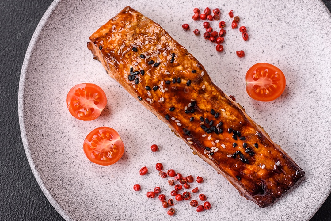 Delicioso salmão vermelho grelhado com molho e gergelim, especiarias e ervas sobre um fundo escuro de concreto