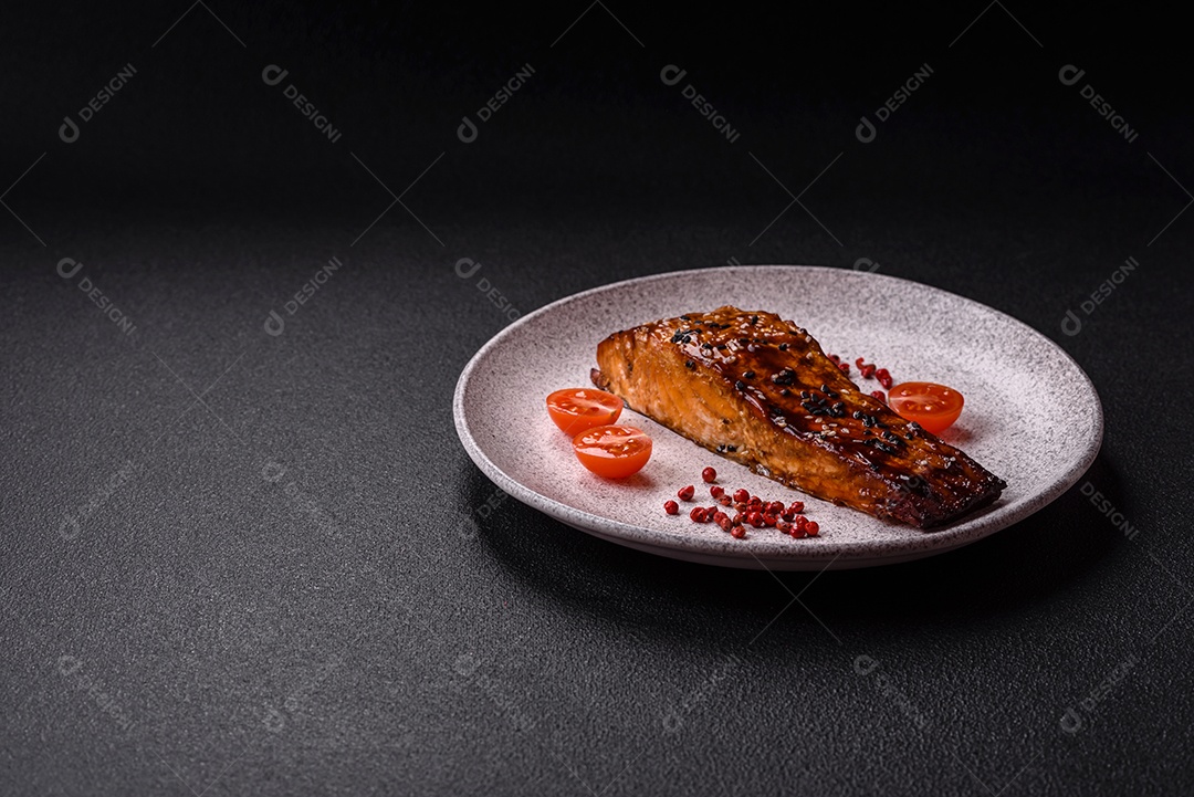 Delicioso salmão vermelho grelhado com molho e gergelim, especiarias e ervas sobre um fundo escuro de concreto