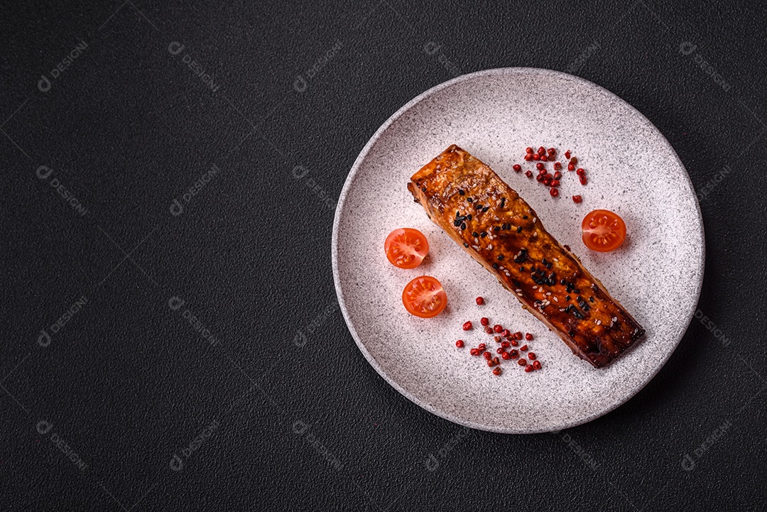 Delicioso salmão vermelho grelhado com molho e gergelim, especiarias e ervas sobre um fundo escuro de concreto