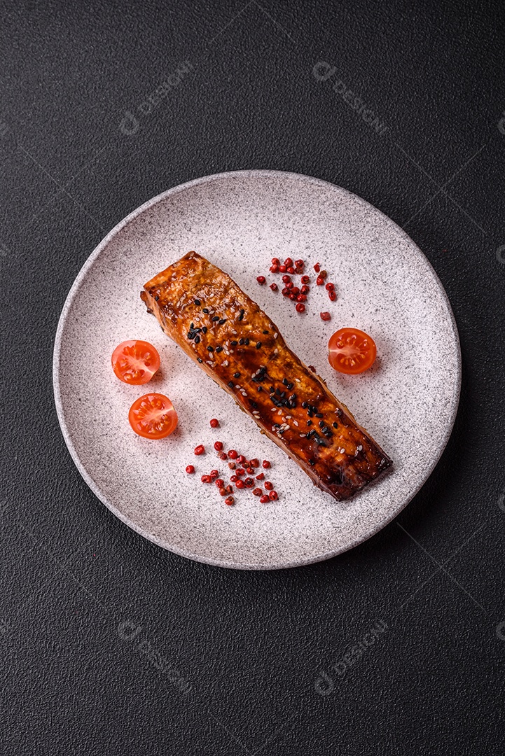 Delicioso salmão vermelho grelhado com molho e gergelim, especiarias e ervas sobre um fundo escuro de concreto