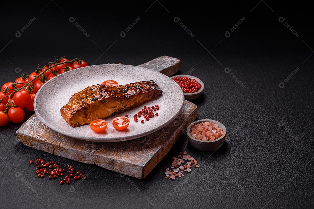 Delicioso salmão vermelho grelhado com molho e gergelim, especiarias e ervas sobre um fundo escuro de concreto