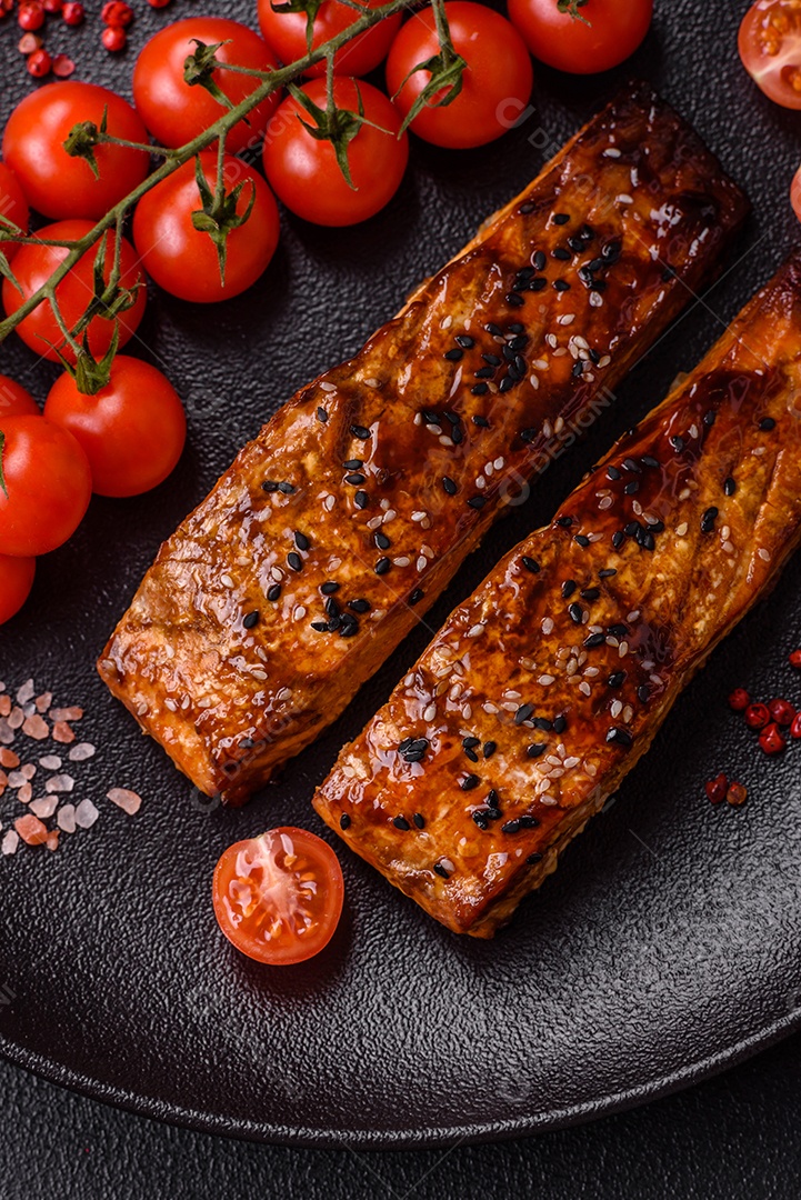 Delicioso salmão vermelho grelhado com molho e gergelim, especiarias e ervas sobre um fundo escuro de concreto
