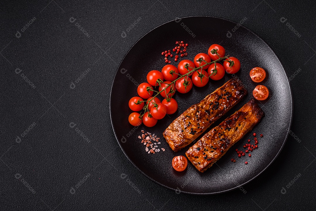 Delicioso salmão vermelho grelhado com molho e gergelim, especiarias e ervas sobre um fundo escuro de concreto