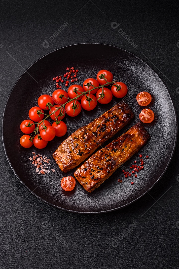 Delicioso salmão vermelho grelhado com molho e gergelim, especiarias e ervas sobre um fundo escuro de concreto