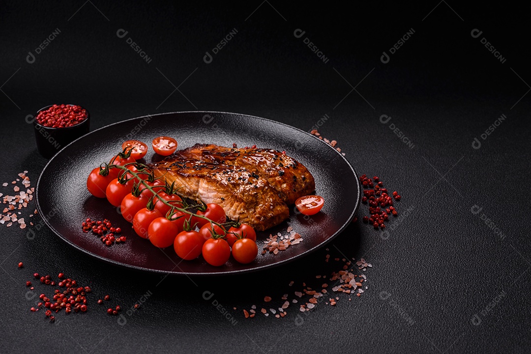 Delicioso salmão vermelho grelhado com molho e gergelim, especiarias e ervas sobre um fundo escuro de concreto