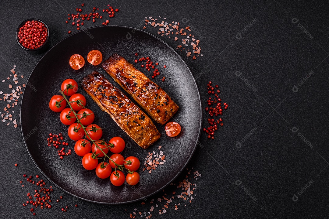 Delicioso salmão vermelho grelhado com molho e gergelim, especiarias e ervas sobre um fundo escuro de concreto