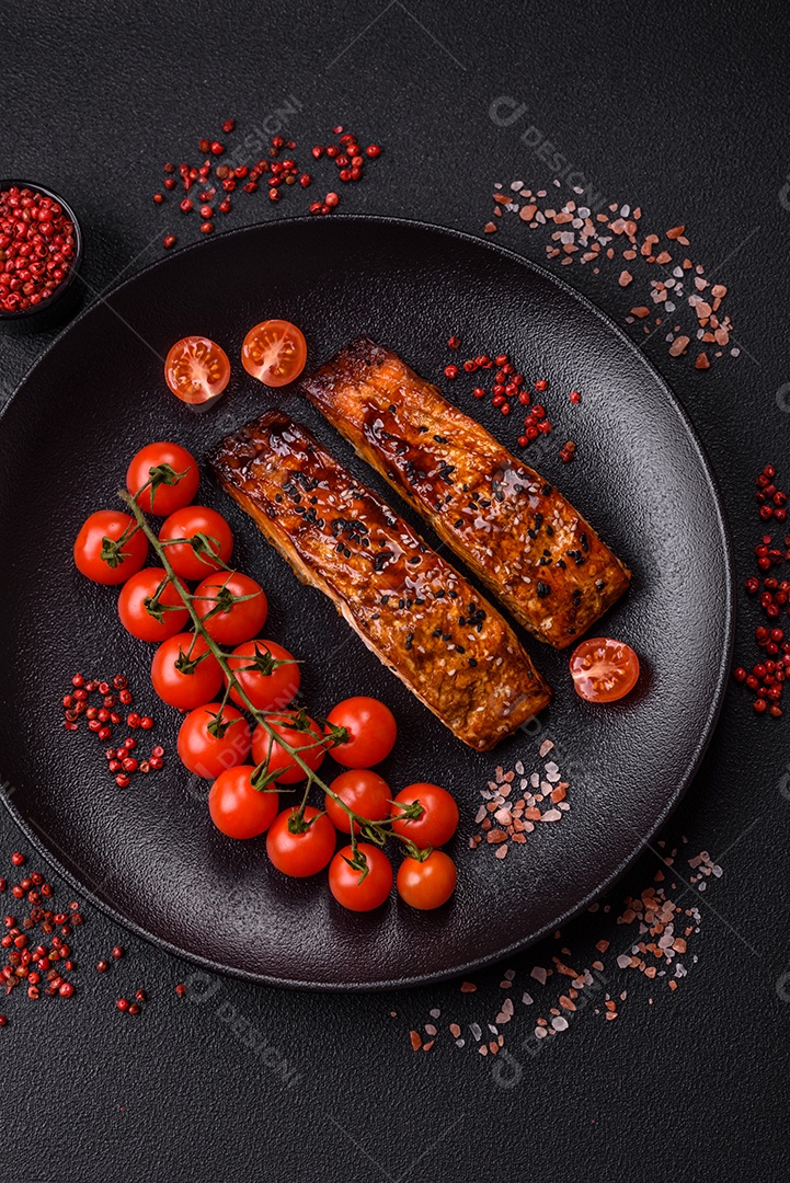 Delicioso salmão vermelho grelhado com molho e gergelim, especiarias e ervas sobre um fundo escuro de concreto