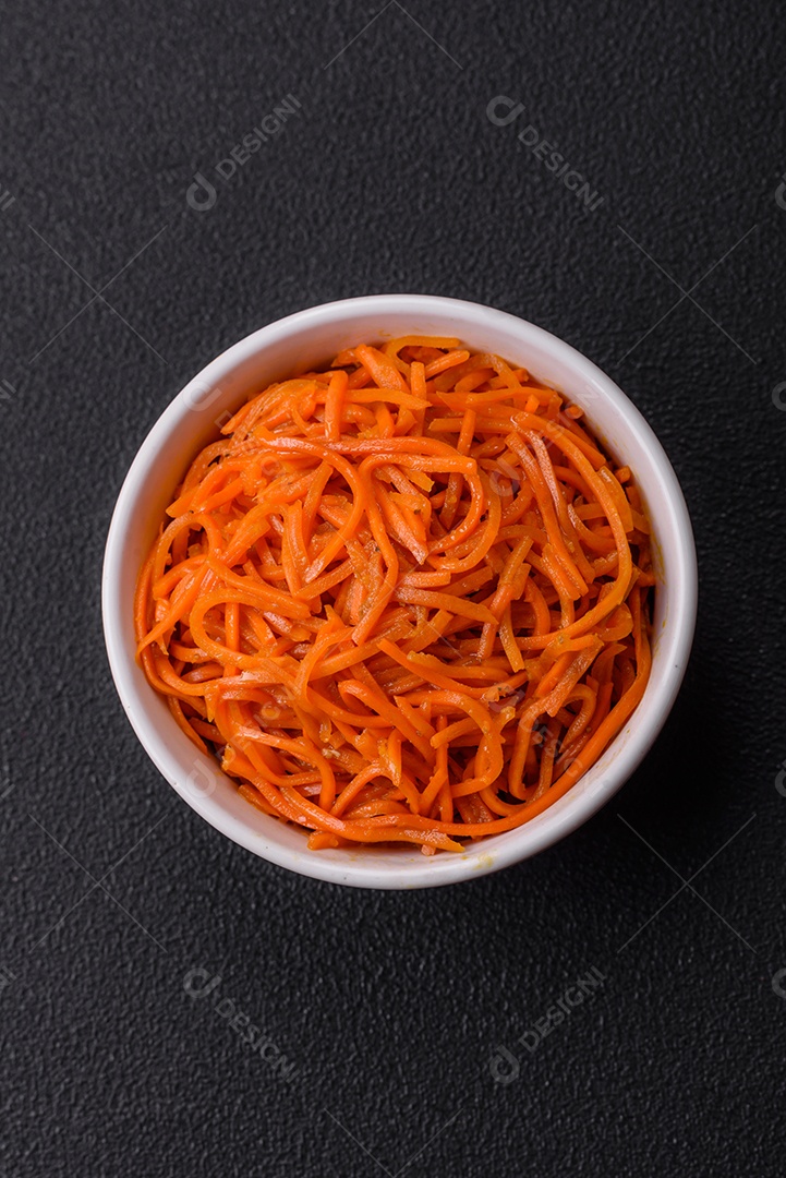 Saborosa cenoura coreana picante com especiarias e ervas em um fundo escuro de concreto. comida asiática