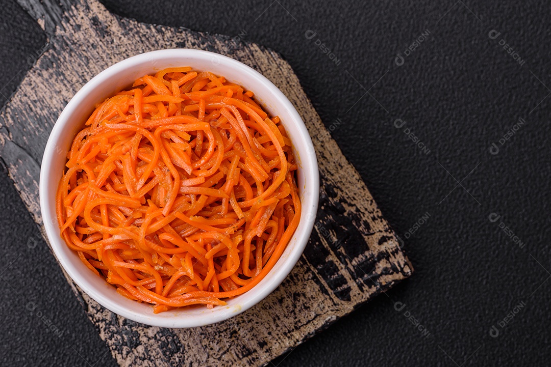 Saborosa cenoura coreana picante com especiarias e ervas em um fundo escuro de concreto. comida asiática