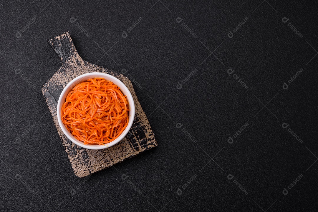 Saborosa cenoura coreana picante com especiarias e ervas em um fundo escuro de concreto. comida asiática