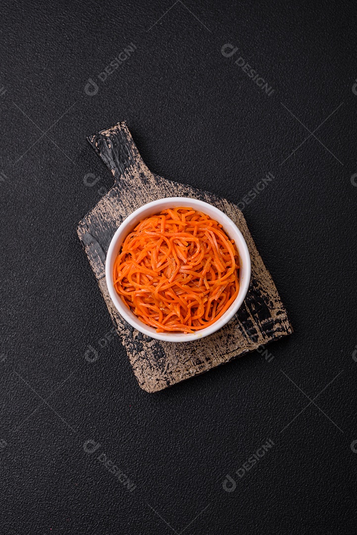 Saborosa cenoura coreana picante com especiarias e ervas em um fundo escuro de concreto. comida asiática