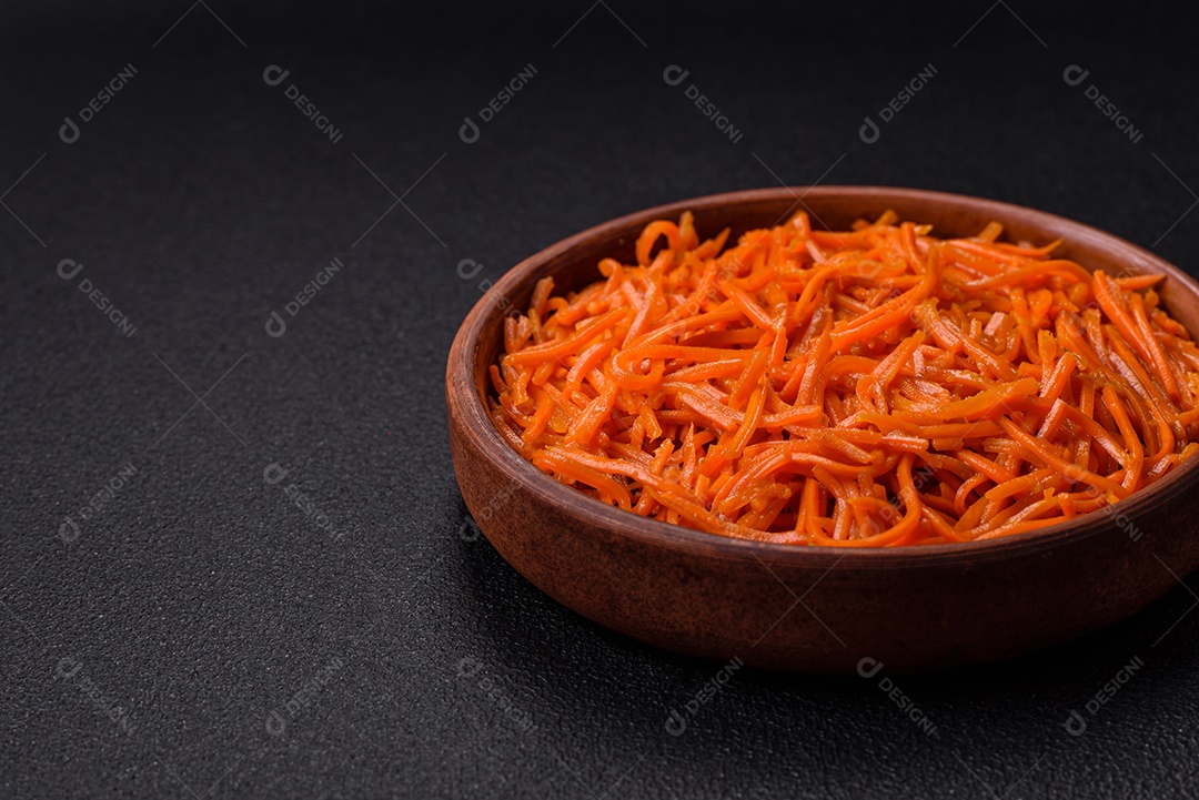 Saborosa cenoura coreana picante com especiarias e ervas em um fundo escuro de concreto. comida asiática