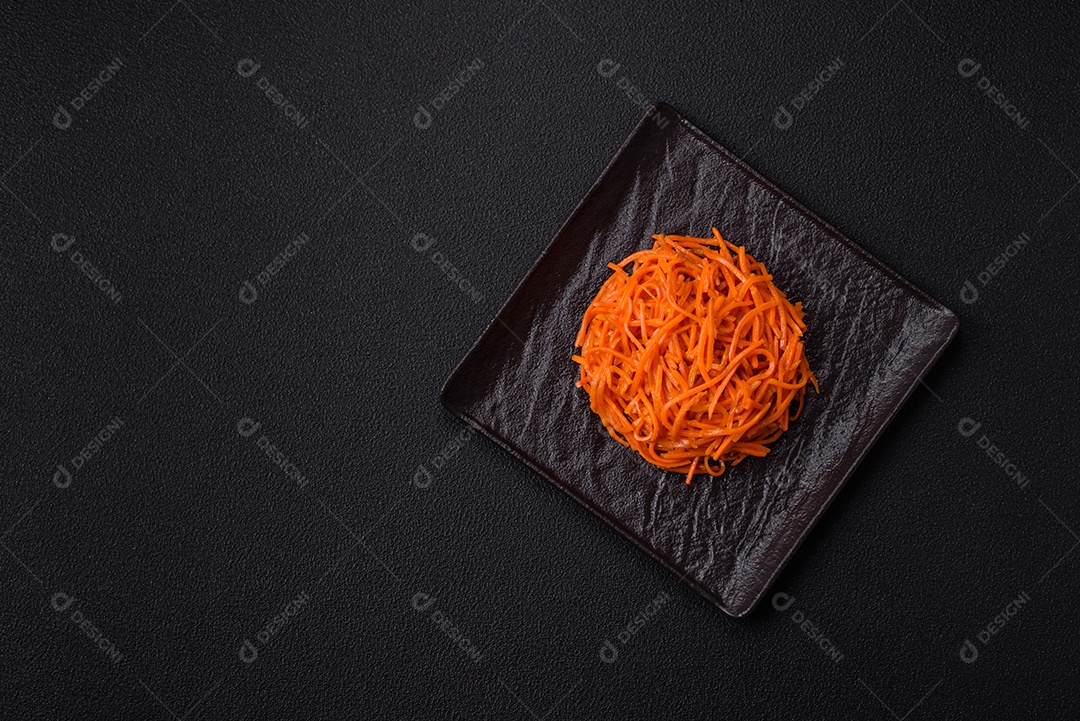 Saborosa cenoura coreana picante com especiarias e ervas em um fundo escuro de concreto. comida asiática