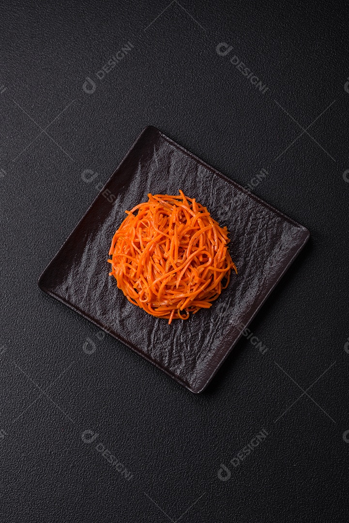 Saborosa cenoura coreana picante com especiarias e ervas em um fundo escuro de concreto. comida asiática